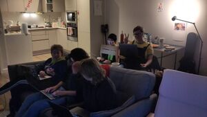 A group of 5 people sit on sofas and chairs in a kitchen living room. They have they laptops out and are ready to start the workshop.
