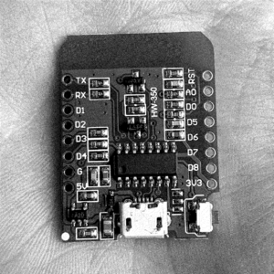 Wemos D1 Mini microcontroller on a hand. The various resistors and other components are visible around the board. There is also a usb port.